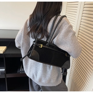 Detail of vintage black baguette bag featuring suede leather contrast and gold buckle