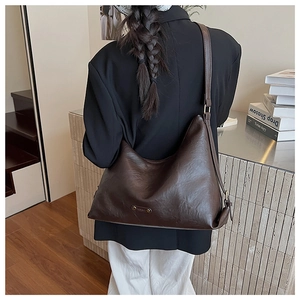 Große braune Shopper-Tasche mit goldener Logo-Plakette und mattem Leder-Finish