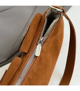 Makroaufnahme des glatten Metallreißverschlusses und braunen Wildleders der Tasche