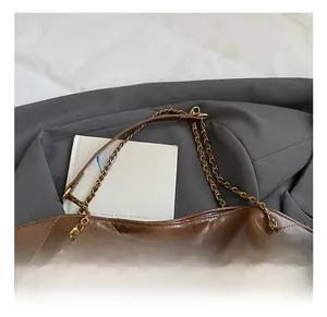 Close-up of dark brown quilted leather tote bag with gold chain strap detail