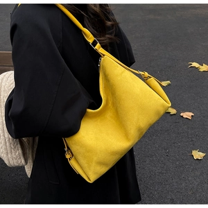 Detalle del bolso tote de ante amarillo con costuras finas y correa ajustable