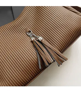 Detail einer braunen Faltenledertasche mit silberner Metallkette und Fransenanhänger