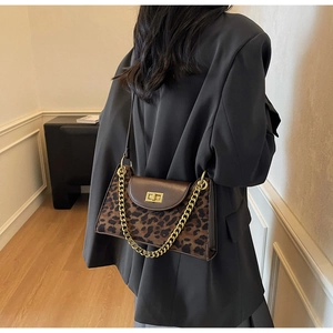 Detail der Schultertasche mit Leopardenmuster, Goldschließe und Kette am Modell