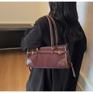 Detail view of brown suede baguette bag with gold buckles and tassels on a model