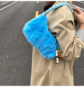 Détail d'un sac à bandoulière en peluche bleue avec poignée tressée et pompon en perles de bois