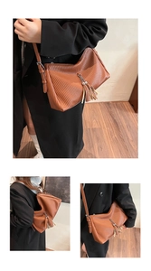 Detail der braunen Leder-Schultertasche mit vertikalen Falten und Quastenanhänger