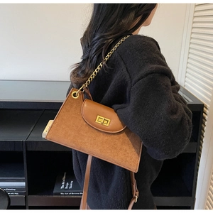 Details einer Vintage Wildledertasche mit goldenem Drehverschluss und Kettenriemen