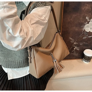 Detailed close-up of brown pleated shoulder bag with silver chain and tassel accents
