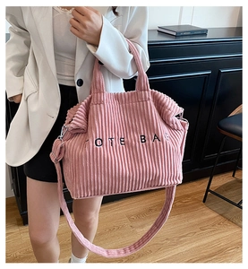 Detailed view of pink corduroy tote bag featuring black embroidered lettering and soft texture