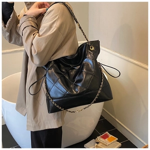 Close-up of black quilted leather tote bag with chain strap and drawstring side detail