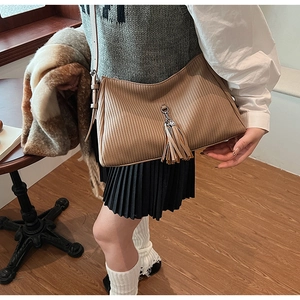 Detail of khaki pleated shoulder bag with leather tassel pendant and vertical texture