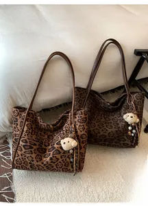 Detail of vintage leopard print tote bags with brown leather straps and plush bear charm