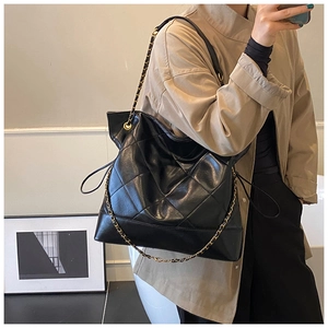 Detail of black quilted leather tote bag featuring gold chain strap and drawstring closure