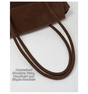 Detail of round double shoulder straps and matte suede texture on coffee brown tote bag