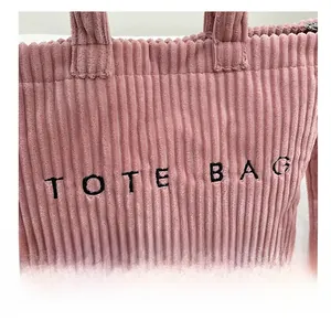 Detail of pink corduroy tote bag featuring black letter embroidery and fine fabric texture