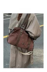 Outdoor shot of large brown matte tote bag with woven shoulder strap on trench coat