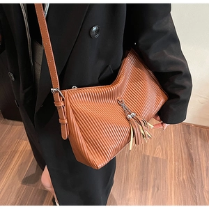 Detail of pleated brown leather shoulder bag with tassels and silver metal chain strap
