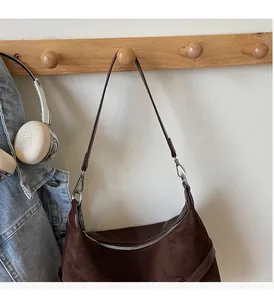 Détail d'un sac d'épaule vintage en daim marron avec bandoulière en cuir lisse