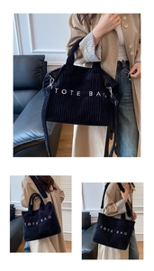 Detailed texture of black corduroy tote bag with white TOTE BAG embroidery and strap