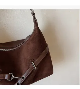 Gros plan détaillé sur la texture en daim marron et les finitions métalliques du sac à main