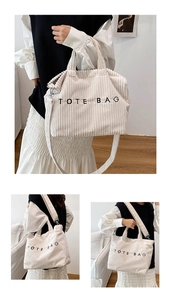 Detailed close-up of corduroy tote bag texture with embroidered lettering and shoulder strap