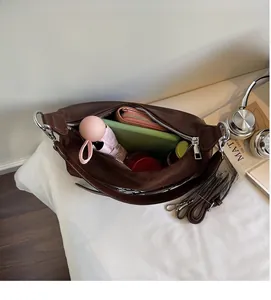Vue de dessus montrant l'intérieur spacieux du sac à bandoulière marron avec objets