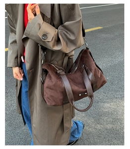 Detail view of large brown suede tote bag with metal zipper and woven strap on model