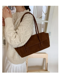 Détail d'un sac porté épaule en daim marron foncé avec fines anses sur tricot