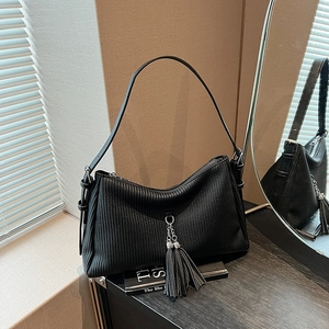 Detail der schwarzen Cord-Schultertasche mit vertikaler Textur und silberner Quaste