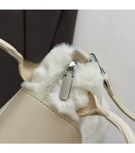 Detail of smooth silver zipper and soft off-white faux fur texture on a shoulder bag