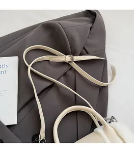 Detail of adjustable leather strap and silver buckle on white plush tote bag