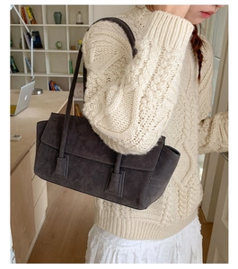 Detail of dark grey suede shoulder bag featuring a rectangular flap and dual straps