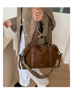 Detail of retro dark brown Boston bag with matte finish and wide woven shoulder strap