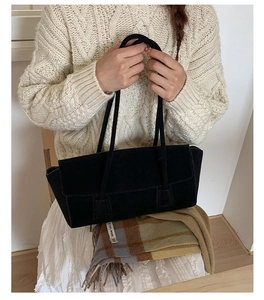Détail d'un sac cabas en daim noir avec fines anses dans une tenue d'automne chic