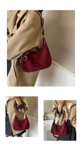 Detail of burgundy suede crescent bag featuring contrast woven rope and metal rings