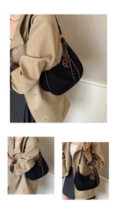 Detail of black suede hobo bag with a decorative pretzel knot and braided rope strap