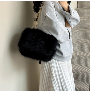 Detail of soft black faux fur shoulder bag with an elegant golden metal chain strap