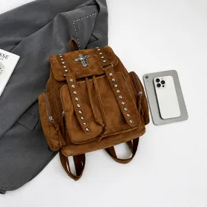 Close-up of brown suede backpack with metallic rivets and cross detail on front flap