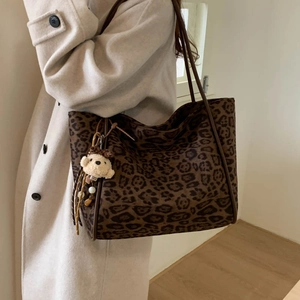 Detail of leopard print tote bag with brown faux fur texture and cute plush bear charm
