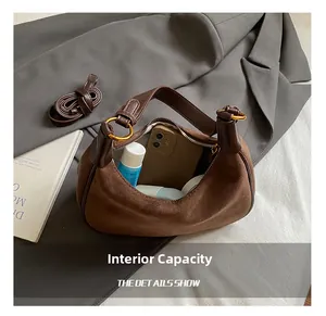 Detail view of large brown suede hobo bag interior showing daily essentials and accessories