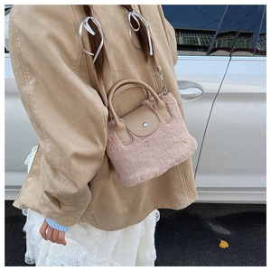 Detail of pink faux fur handbag with brown leather flap and silver metal hooks