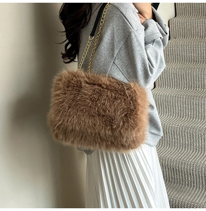Close-up of a brown plush faux fur tote bag with a golden chain strap on a model