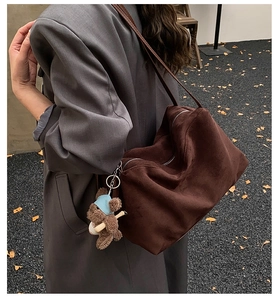 Detail of soft chocolate brown suede tote bag with a cute teddy bear charm