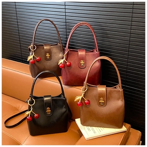 Macro detail of retro bucket bags showing glossy faux leather, gold locks and cherry charms