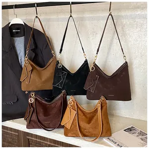 Detail of matte suede tote bags in earthy tones featuring small envelope pouches