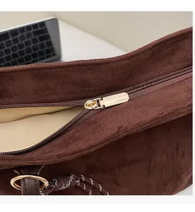 Nahaufnahme des goldfarbenen Reißverschlusses und Innenfutters der braunen Wildledertasche