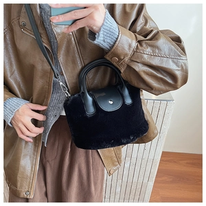Detailed texture of black plush faux fur handbag with leather flap and metallic clasp