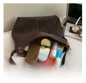 Detailansicht der großen dunkelbraunen Hobo-Tasche mit geräumigem Innenraum und Utensilien