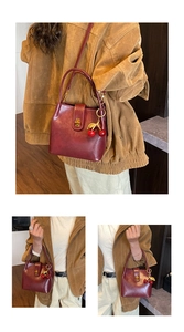 Detail of vintage burgundy bucket bag featuring cherry pendant and gold twist lock closure