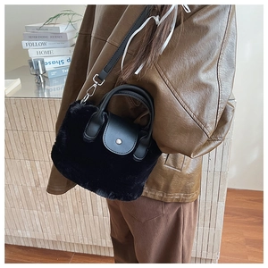 Detail of black faux fur mini bag with leather flap and silver buckle on a brown coat